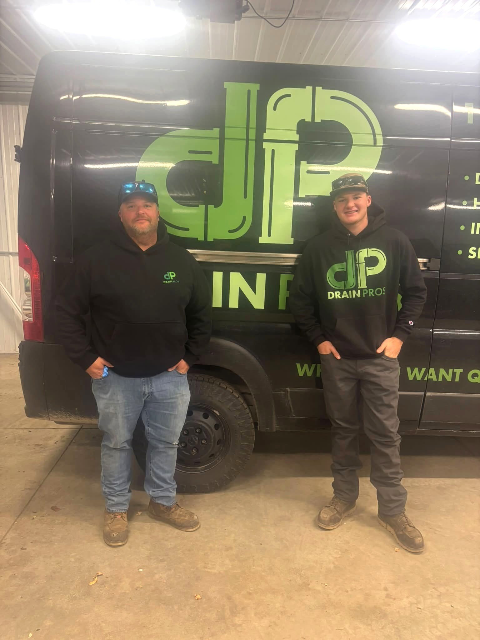 Drain Pros team members standing in front of their branded service van